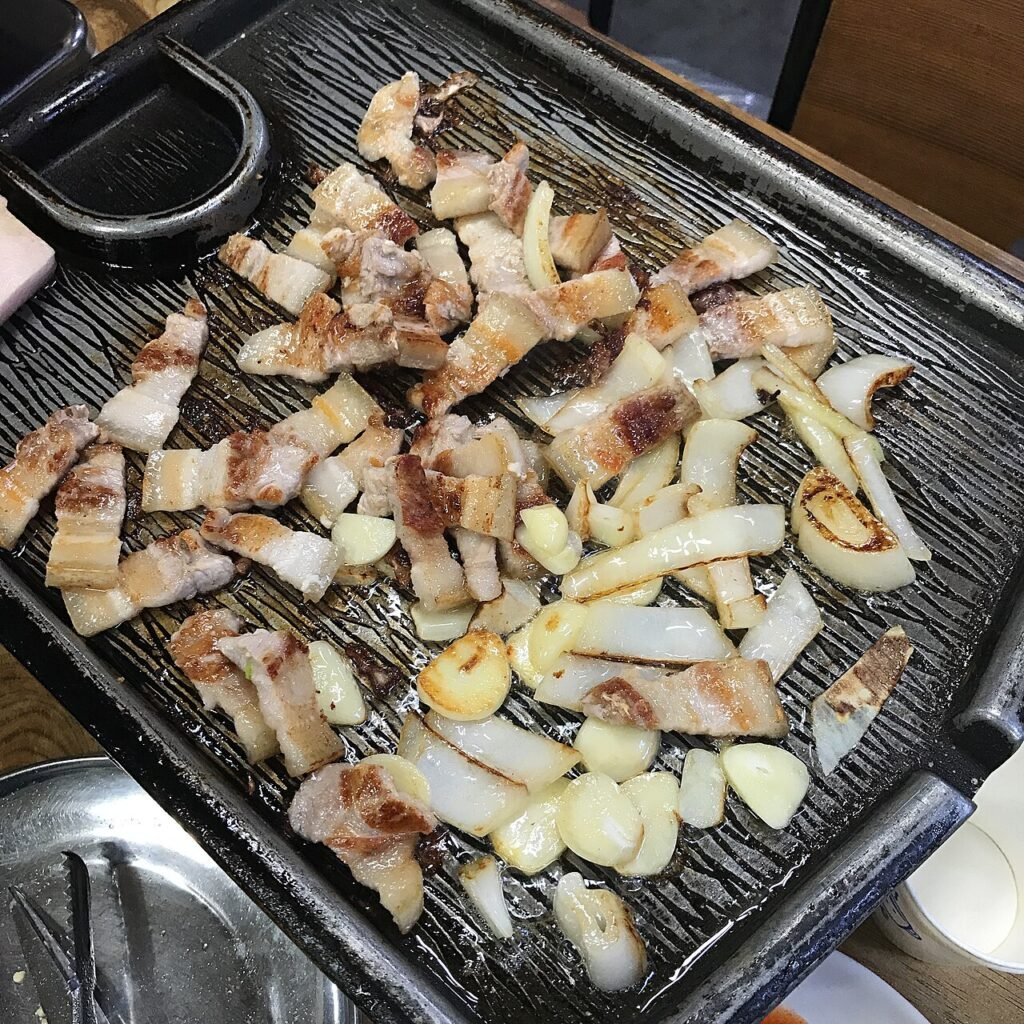 Thick pork belly grilling over charcoal, the way Jeju's Black Pork Street serves it