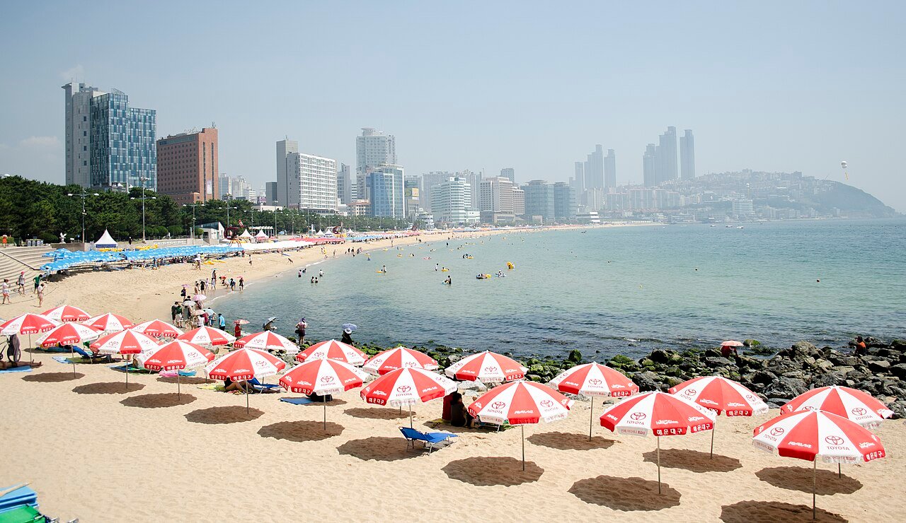 Beachgoers on Haeundae Beach with high-rise towers of Busan in view