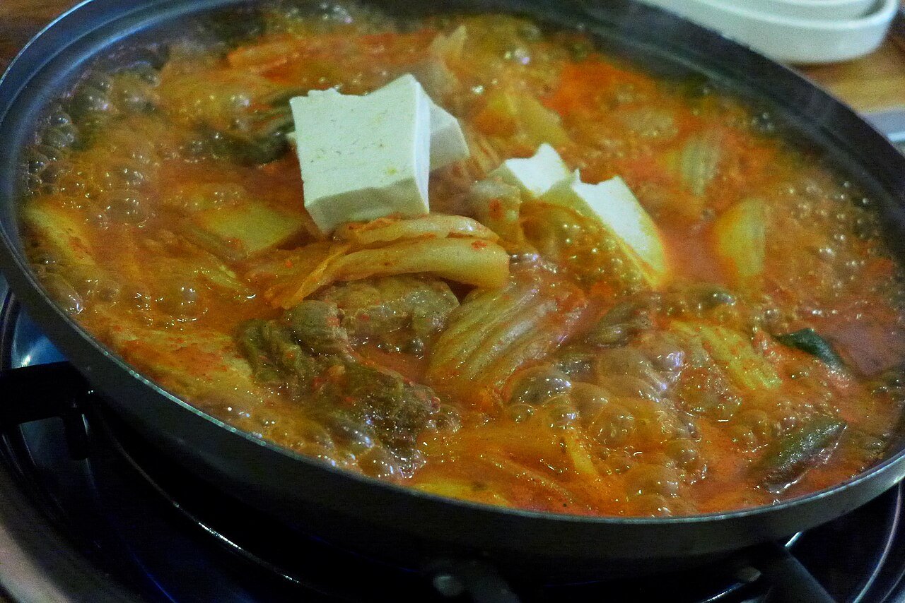 Bubbling kimchi jjigae stew served with rice and side dishes