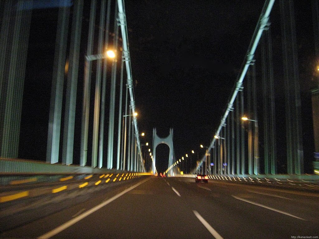 The roadway of Gwangan Bridge at night between lit suspension cables and towers