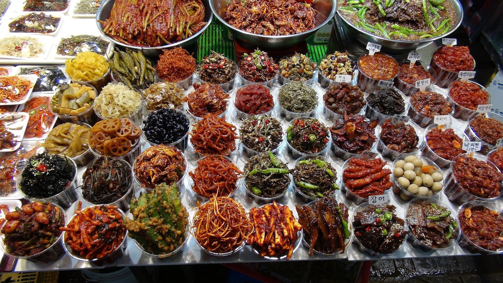 Small bowls of banchan side dishes laid out at a traditional market