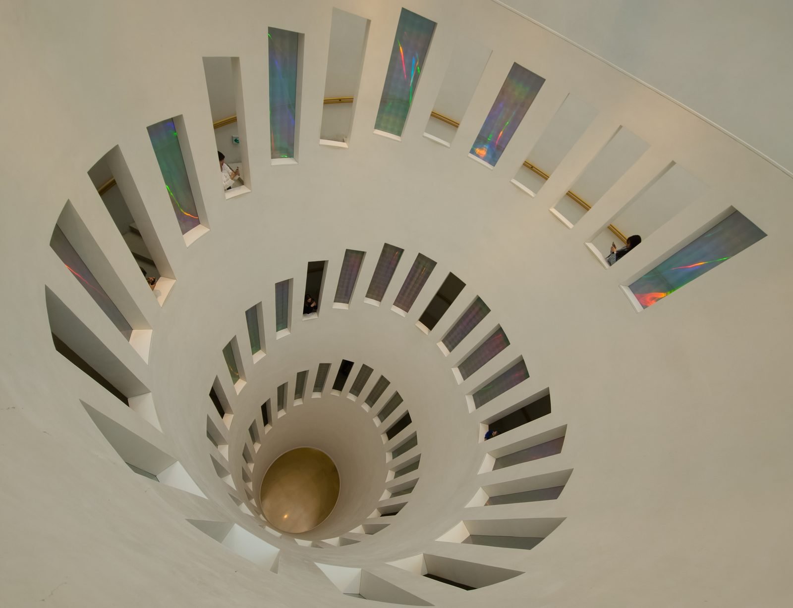 Aerial view down a spiral staircase lined with iridescent glass panels inside Leeum museum in Seoul