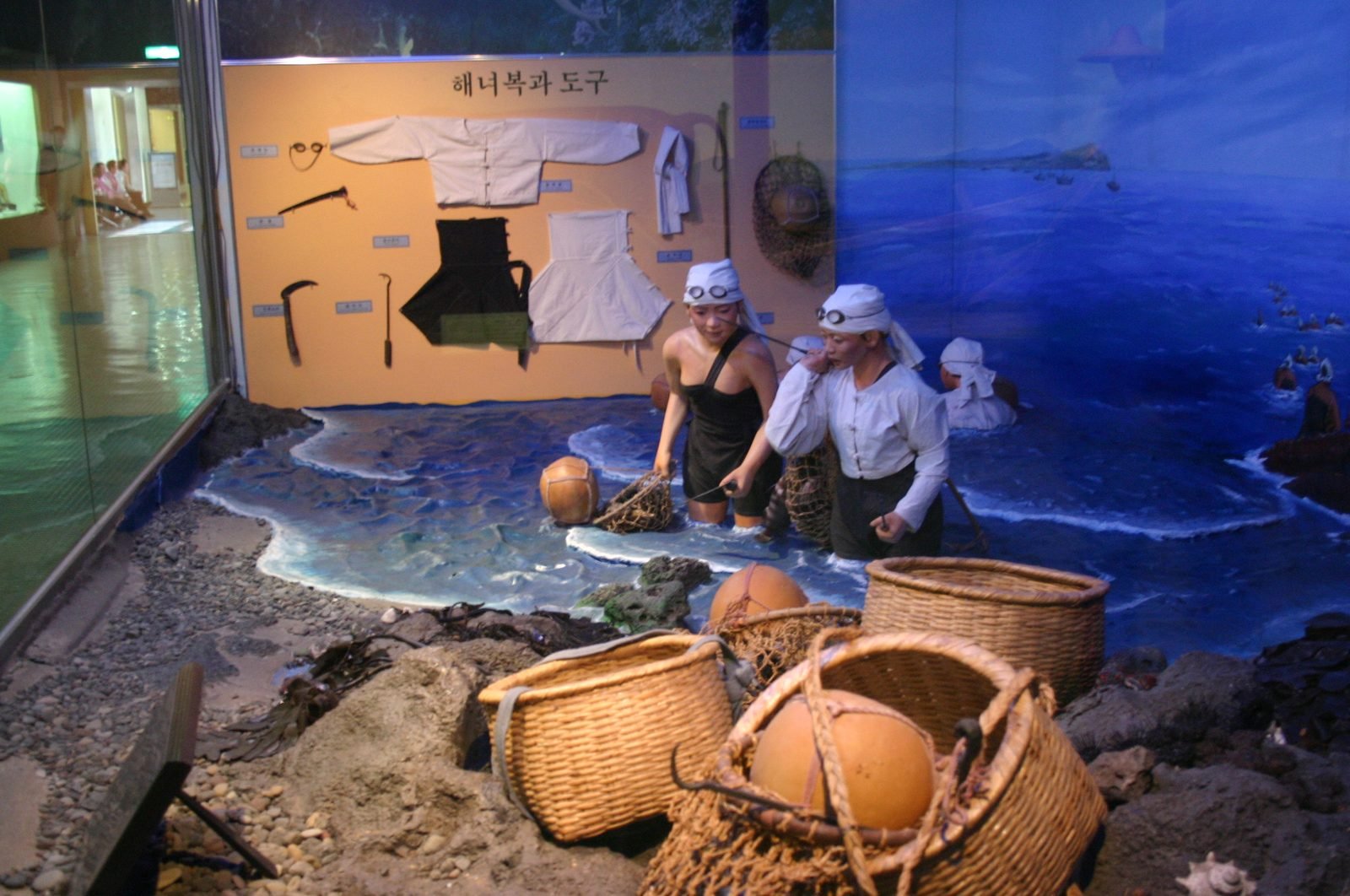 Museum display of white diving clothes, hooks and woven floats used by Jeju's women divers