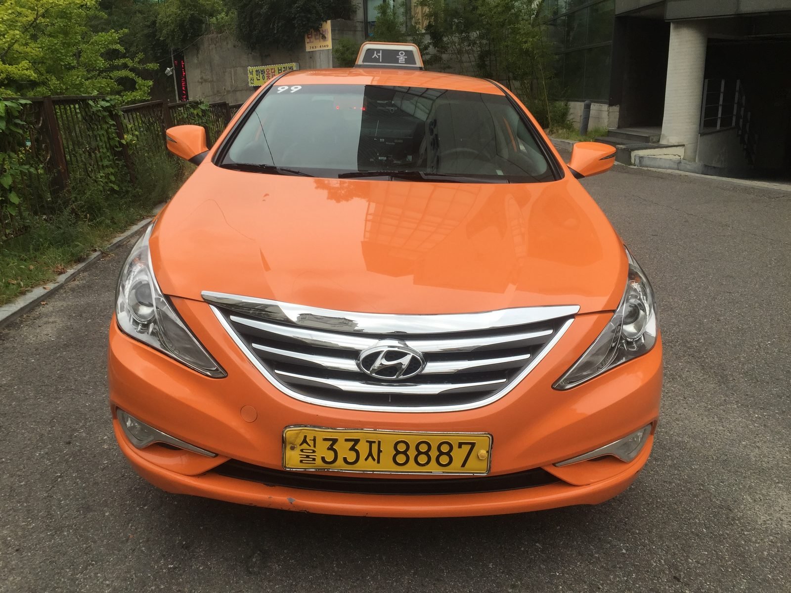 An orange Hyundai Sonata taxi driving on a Seoul street